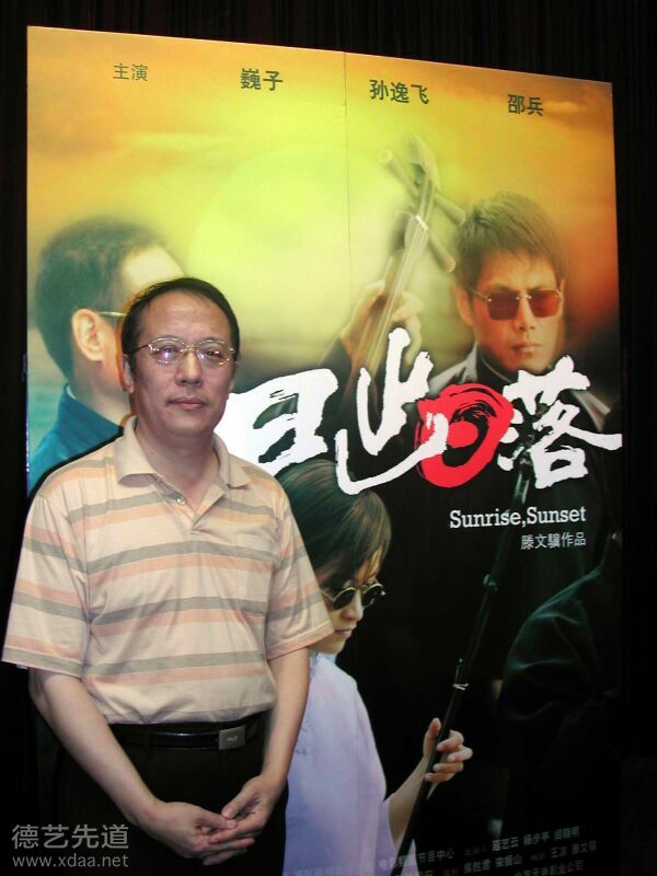 2005年_纪清远为电影《日出日落》题写片头，身后的海报书法为纪清远所题